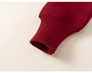 Détail de la robe en tricot rouge montrant les poignets côtelés et la texture épaisse