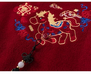 Detail of red winter jacket featuring traditional horse embroidery and Chinese knot pendant