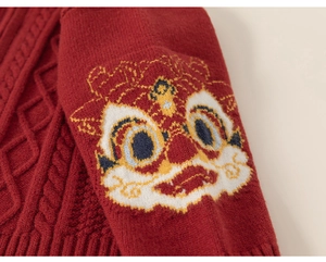 Détail d'un pull en maille rouge avec motif de danse du lion et texture torsadée épaisse
