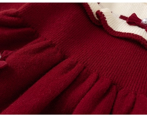 Détail d'une robe en tricot rouge avec col à volants crème et nœud en velours