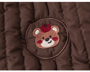 Détail du tissu matelassé marron avec broderie d'ours mignon sur pantalon enfant
