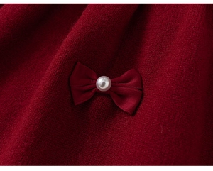 Détail d'une robe rouge en tricot avec nœud en soie et ornement de perle blanche