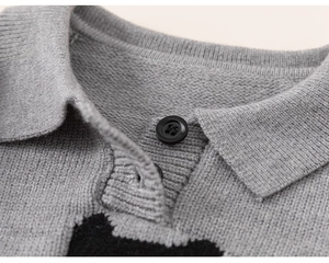 Detail of grey knitted polo collar with a black button and soft texture on children sweater