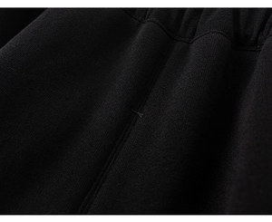 Close-up of black knitted fabric texture with elastic waistband and reinforced stitching