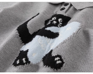 Detail of grey knitted polo sweater showing jacquard cat pattern and collar buttons