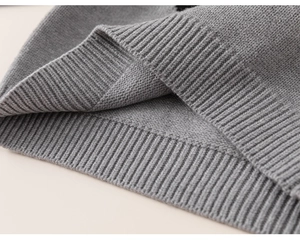 Detailed macro view of the grey fine-knit sweater showing the ribbed elastic hem texture