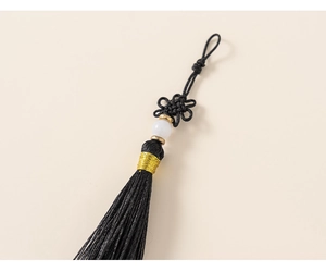 Detail of Chinese knot pendant with gold wire wrap and black silk tassels for kids outfit