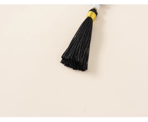 Detail of traditional black tassel with golden binding and white bead on kids' winter outfit