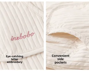 Détail du tissu matelassé beige avec broderie rose et poches latérales fonctionnelles