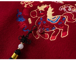 Detail of red Chinese New Year outfit featuring horse embroidery and tassel with bead