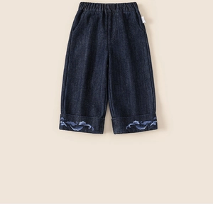 Macro view of kids wide-leg denim pants featuring detailed light blue cloud embroidery