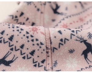 Macro shot of warm pink fleece fabric with blue reindeer pattern and soft inner stitching