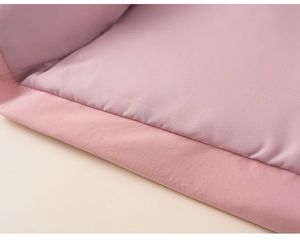 Close-up of pink padded winter jacket showing high-quality stitching and woven fabric detail