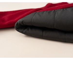 Detailed close-up of red wool fabric with black quilted lining on winter jacket