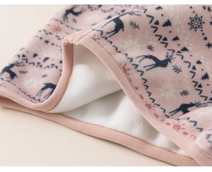 Detail of pink fleece fabric featuring navy reindeer and white snowflake winter patterns