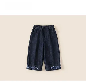 Close-up of children's dark blue denim pants featuring light blue cloud wave embroidery