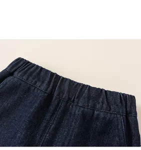 Detail view of elastic waistband and stitching on dark blue denim fabric for kids