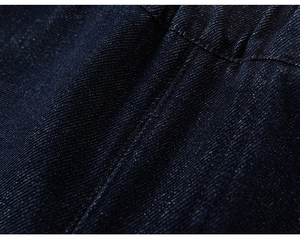 Macro detail of dark blue denim fabric showing twill weave and high-quality stitching