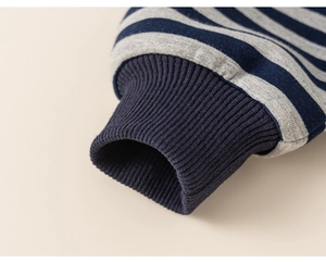 Detail view of navy and grey striped cotton sleeve with elastic ribbed cuffs on a warm kid sweater