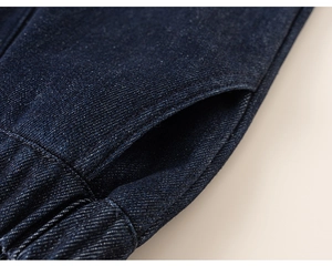 Detail of dark blue denim trousers featuring elastic waistband and side pocket textures