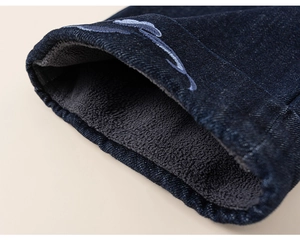 Detail of kids winter denim jacket with warm grey fleece lining and blue embroidery