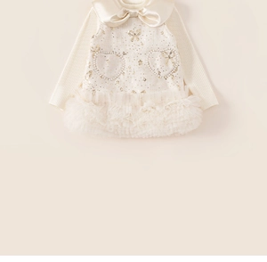 Détails d'une robe crème pour fille avec nœud en satin et broderies de perles en cœur