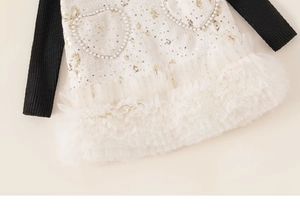 Détail d'une robe en tweed pour fille avec cœurs en perles et ourlet en tulle
