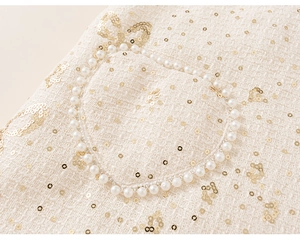 Détail du tissu en tweed avec broderie nœud à paillettes et bordure en perles
