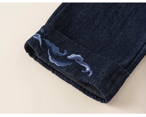 Close-up of girl's dark denim jeans with wave embroidery and warm fleece lining