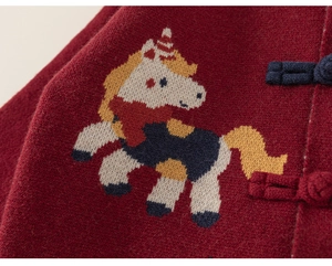 Macro detail van de rode gebreide trui met pixel eenhoorn en traditionele knoopsluiting