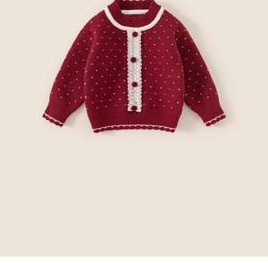 Detail of red knitted girls sweater with white polka dots and delicate lace trim edges