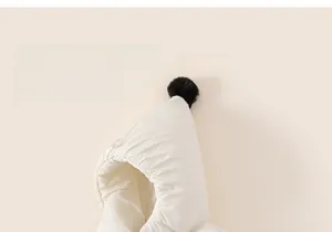 Detailed view of cream hooded jacket featuring elastic edges and a black faux fur pom-pom