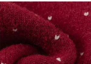 Detail of red knit fabric featuring white heart patterns and soft thick wool texture