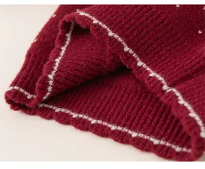 Close-up of red knitted sweater hem featuring delicate white stitched texture detail