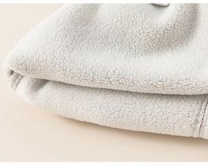 Close-up of soft beige sherpa fleece texture on warm knit sweater for children