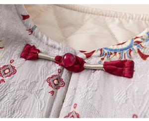 Detail of traditional Chinese frog button on warm quilted vest with floral embroidery