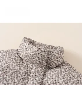 Close-up of floral print details and stitching on a warm beige padded winter jacket