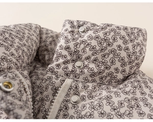 Detail of floral puffer jacket showing silver snap buttons and zipper closure