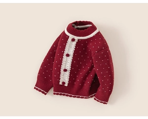 Detail of red knitted girl sweater with white polka dots and delicate lace trim accents