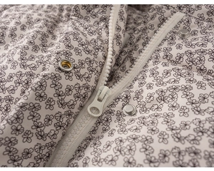 Detail of floral quilted jacket featuring silver snaps and white zipper closure