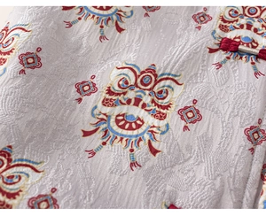 Detailed close-up of silk-like brocade fabric with traditional lion dance embroidery