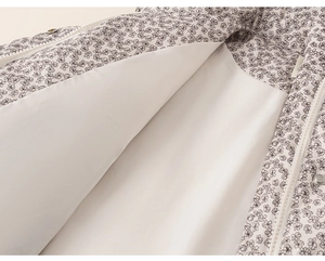 Detail of floral baby jacket featuring metal zipper and snap button on white lining