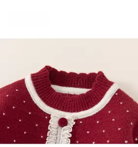 Detail of red knit sweater collar with white heart patterns and lace trimming