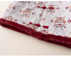 Detailed view of silver brocade fabric with lion embroidery and red faux fur trim