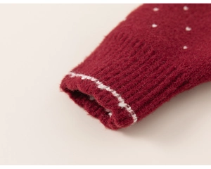 Close-up of red knitted sweater cuff with white wavy trim and soft plush texture