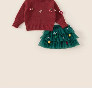 Close-up of festive red knit sweater with snowman applique and green tutu tulle skirt