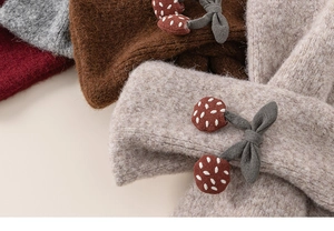 Detailed close-up of soft knit scarves with cherry embroidery and colorful textures