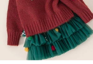 Detail of red knit sweater and green mesh tutu skirt with colorful plush pom-poms