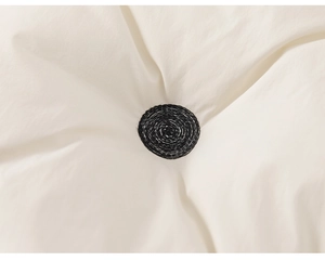 Macro view of black circular embroidery on soft white quilted cotton fabric detail