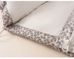 Detailed close-up of floral print jacket fabric with white zipper and adjustable drawstring